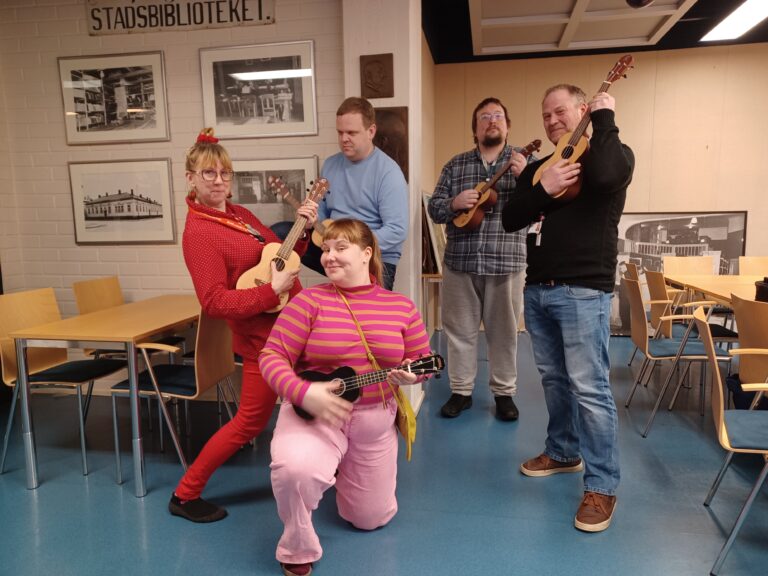 Kirjaston henkilökunta näyttää mallia ukulelen soittoon